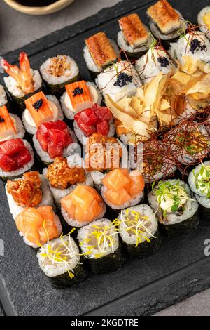 Sushi Set di vari prodotti su un piatto di pietra nera. Sfocatura dello sfondo e messa a fuoco selettiva Foto Stock