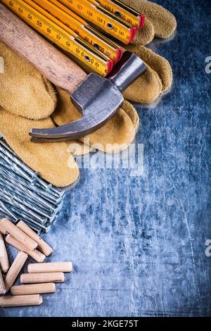 Guanti di protezione in pelle martellatrice pila di chiodi e tasselli metallici graffiati con superficie metallica vista dall'alto concetto di costruzione. Foto Stock