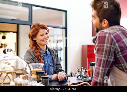 Servizio con sorriso sincero. una giovane donna che ordina un caffè in un bar. Foto Stock