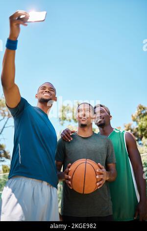 Selfie, basket e squadra con telefono sul campo a gioco, allenamento o pratica. Fitness, sport e atleti africani che scattano foto per i social media su Foto Stock