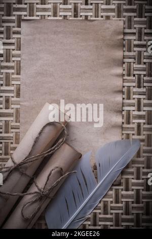 Piuma di carta arrotolata a foglio bianco medievale su tappetino in legno di vimini. Foto Stock