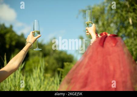 Bicchieri di champagne alzati per ragazze. Alcol in mano. Bevande alla festa. Le bridesmaids alzano il pane tostato. Foto Stock