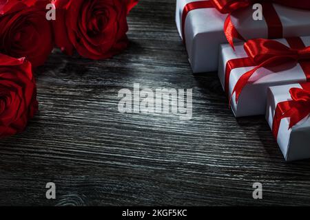 Set di scatole regalo bianche mazzo di rose rosse su asse di legno. Foto Stock