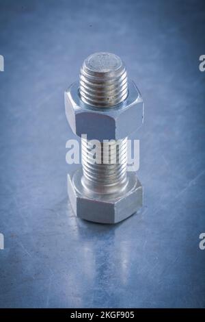 Bullone e dado filettato in acciaio su fondo metallico. Foto Stock