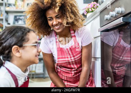 bella scena di una madre e di una figlia che preparano il cibo in cucina, la famiglia multirazziale cucina a casa Foto Stock