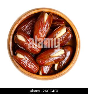 Datteri farciti di mandorle, in una ciotola di legno. Deglet Datteri secchi, tagliati aperti e snocciolati, poi ripieni di mandorle intere sbollite. Foto Stock
