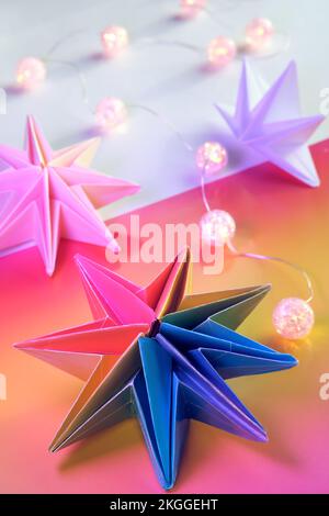 Vibranti stelle di carta origami al neon arcobaleno. LGBTQ Community arcobaleno bandiera colori. Fatto a mano DIY decorazione natalizia. Le stelle di Natale fatte da sé sono fatte da vibrante Foto Stock