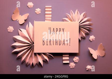 Carta beige compleanno. Ventilatori di carta, farfalle, fiori. Cornice decorativa intorno al biglietto con testo didascalia di saluto Buon compleanno. Piatto con molla Foto Stock