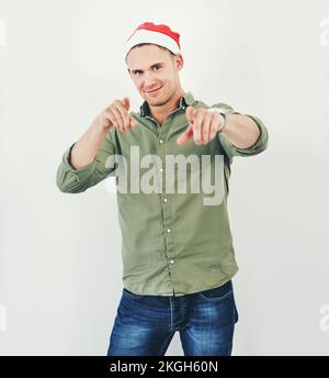 Natale, ritratto e festa con un uomo modello in studio su uno sfondo grigio indossare un cappello per le vacanze. Tradizione, celebrazione e stagioni Foto Stock