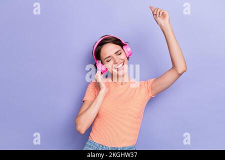 Foto di allegro felice overjoyed signora indossare abiti a righe trendy sollevare mano ascoltare melodia canzone isolato su sfondo di colore viola Foto Stock