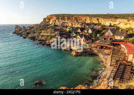 Il-Mellieha, Malta - Vista panoramica dello skyline del famoso Popeye Village a Anchor Bay al tramonto. Foto Stock