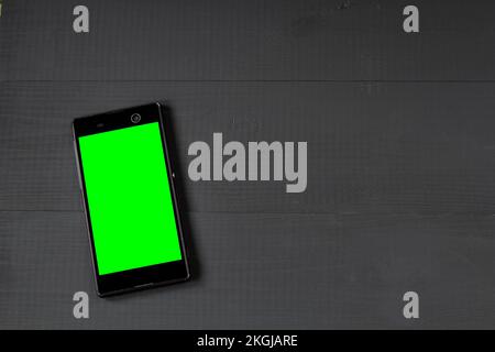 smartphone con schermo verde su tavolo di legno Foto Stock