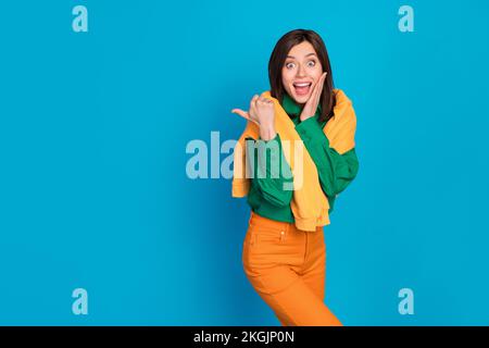 Foto di sorprendente positivo overjoyed signora indossare abiti alla moda braccio diretto vuoto spazio fresco proposta isolata su sfondo di colore blu Foto Stock