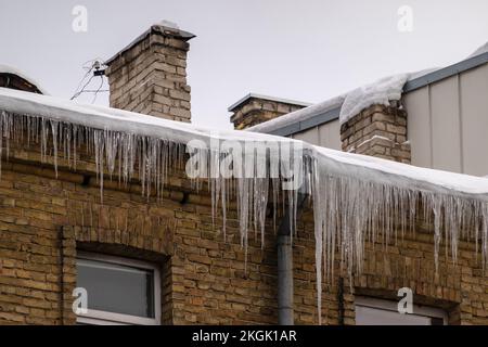 Piciclette affilate appese sul bordo del tetto. Sciogliendo la neve si forma un icicolo. Foto Stock