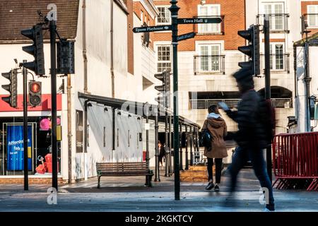 Epsom, Surrey, Londra Regno Unito, novembre 20 2022, Donna croossing Road Man Walking Past Using Mobile Phone or smartphone on A Town Centre High Street Foto Stock