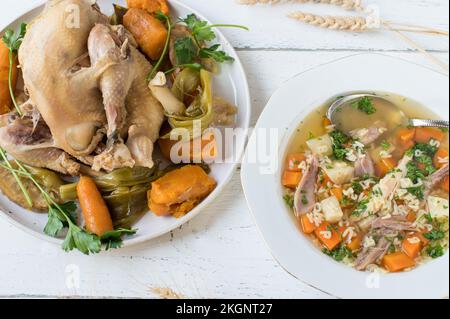 Piatto con zuppa di pollo appena cotta con pasta Alphabet e gallina bollita con verdure su fondo di legno bianco. Giacitura piatta Foto Stock