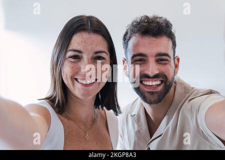 Colleghi di lavoro felici che prendono selfie in ufficio Foto Stock