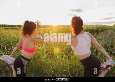 Donna con istruttore che fa esercizio stretching nella giornata di sole Foto Stock