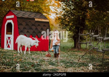 Ragazza felice che indossa costume di volpe in piedi da capra in fattoria Foto Stock