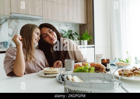 Madre abbracciando la figlia in cucina a casa Foto Stock