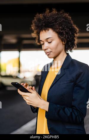 Donna d'affari che indossa un blazer con uno smartphone Foto Stock