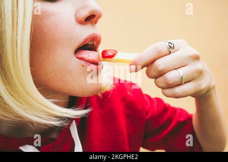 Donna che mangia patatine fritte con ketchup Foto Stock