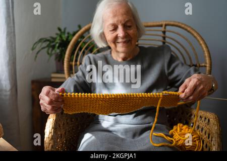 Sciarpa a maglia donna sorridente sulla sedia a casa Foto Stock