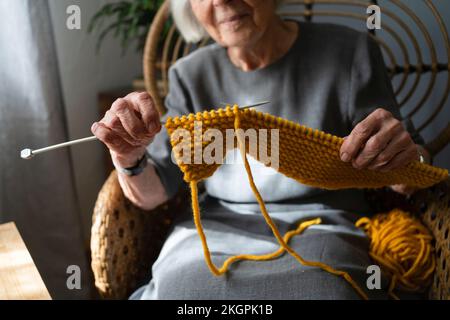 Mani di sciarpa donna anziana a maglia a casa Foto Stock