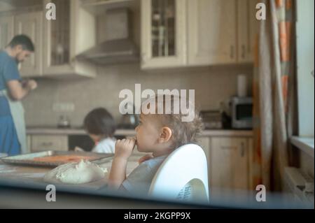 Bambino che mangia la pasta della pizza in cucina visto attraverso la finestra Foto Stock