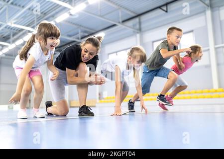 Insegnante che allietano gli studenti alla corsa nel campo sportivo della scuola Foto Stock