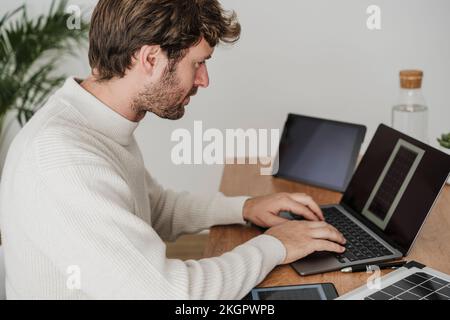 Uomo d'affari che digita sul computer portatile alla scrivania sul posto di lavoro Foto Stock