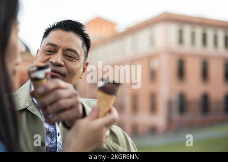 Uomo sorridente e maturo che alimenta il cono gelato alla donna Foto Stock