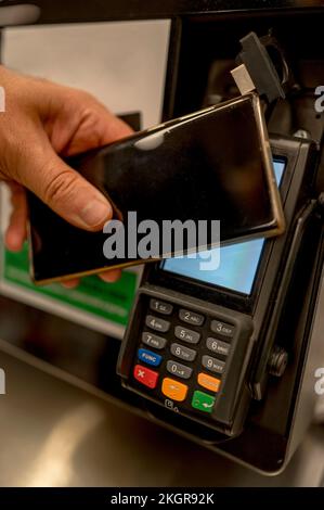 Uomo che usa il metodo TAP per pagare al banco cassa Foto Stock