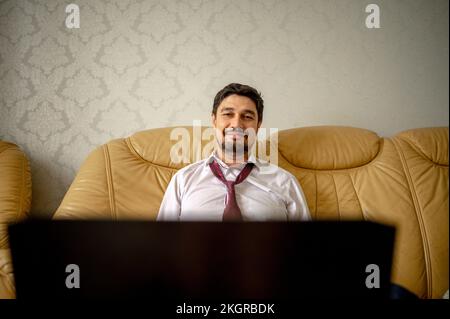 Sorridente freelancer seduto sul divano a casa Foto Stock