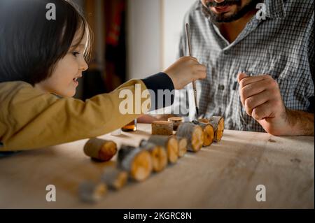Figlio aiutando padre spazzolando olio su legno Foto Stock