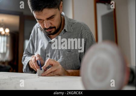 Artigiano che taglia il legno usando l'esablata a casa Foto Stock