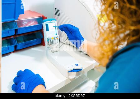 Infermiere che analizza il campione di sangue con l'apparecchiatura in laboratorio Foto Stock