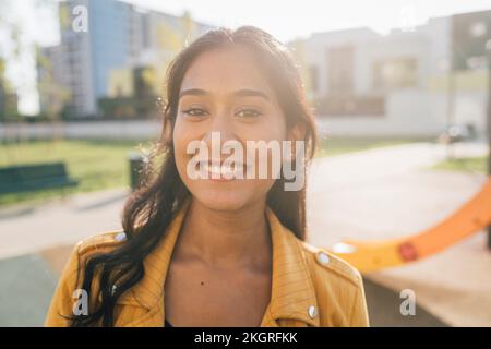 Donna sorridente al parco giochi nelle giornate di sole Foto Stock