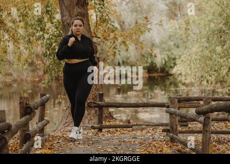 Determinata giovane donna jogging nel parco autunnale Foto Stock