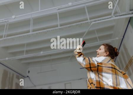 Donna felice in camicia plaid prendere selfie sul telefono cellulare in appartamento Foto Stock