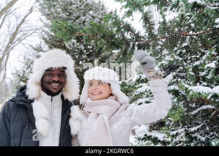 Coppia felice in piedi accanto all'abete nella neve Foto Stock