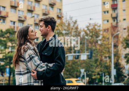 Giovane coppia sorridente che si abbraccia in città Foto Stock