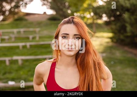 Donna arrossata sicura in piedi nel parco Foto Stock