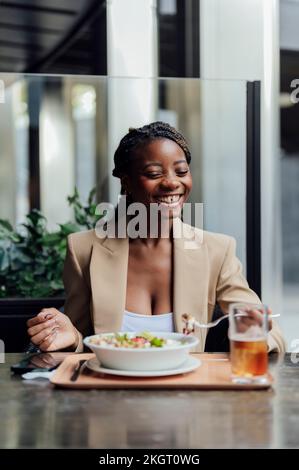 Donna allegra che mangia al bar Foto Stock