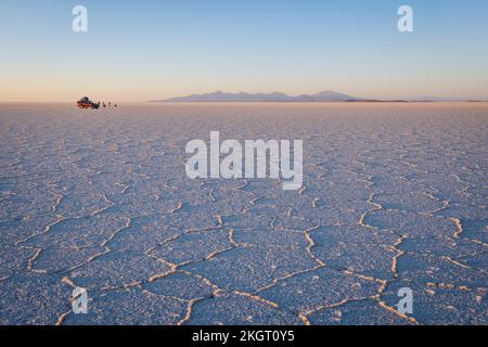 Veicolo fuoristrada e persone a piedi in distanza sul Salar de Uyuni (Uyuni Salt Flat) all'alba, Dipartimento di Potosi, Bolivia Foto Stock