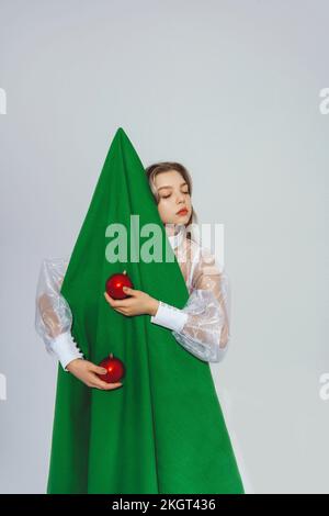 Ragazza adolescente in piedi con albero di Natale artificiale e decorazione su sfondo bianco Foto Stock