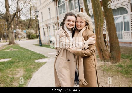 Madre e figlia sorridenti che si abbracciano sul sentiero Foto Stock