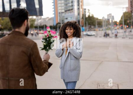 Giovane uomo che dà bouquet di fiori alla donna sul sentiero Foto Stock