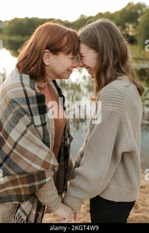 Buona madre e figlia si sfregano il naso vicino al lago Foto Stock