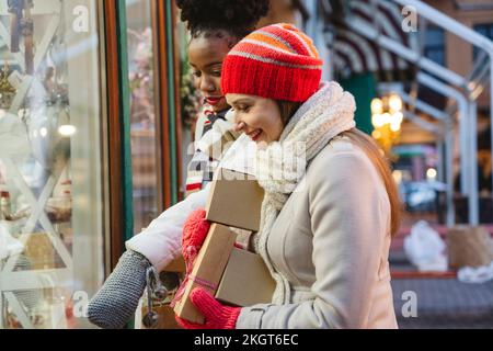 Donne eccitate che fanno shopping in vetrina al festival di Natale Foto Stock